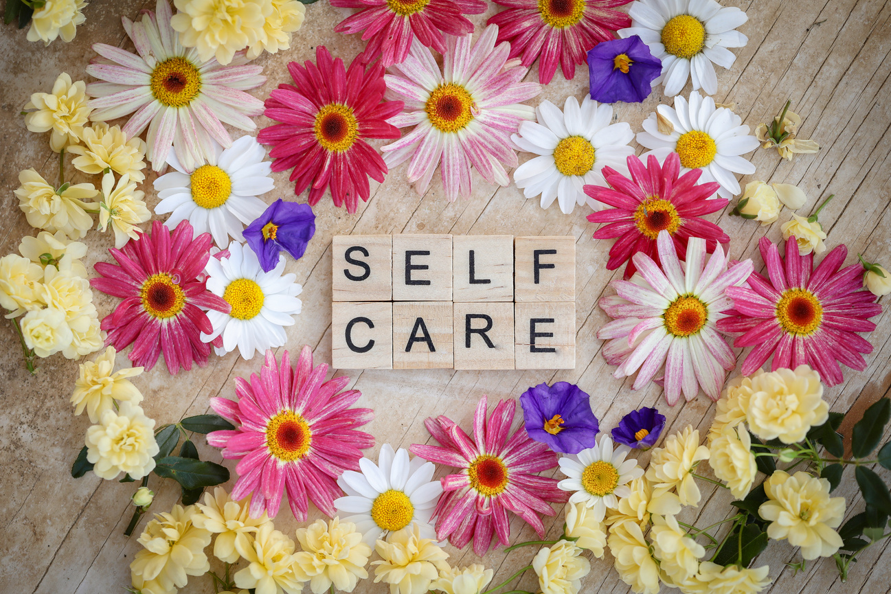 Self Care Written in Wooden Tiles Surrounded by Flowers