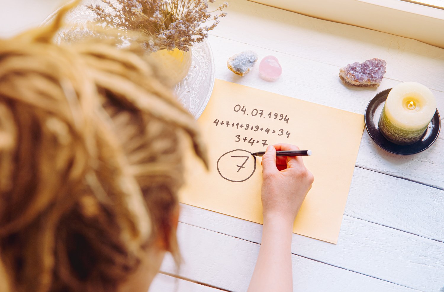 Above view of girl calculate Life path number on paper in home. Spiritual numerology concept.