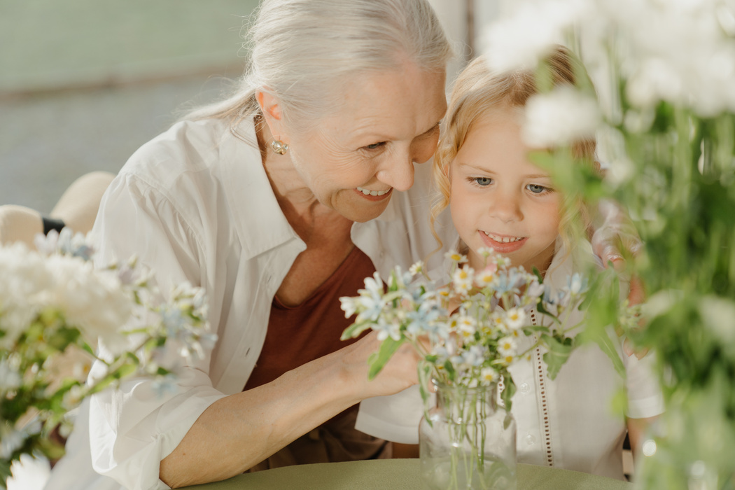 An Elderly Woman and a Child Looking at a Bunch of Flowers